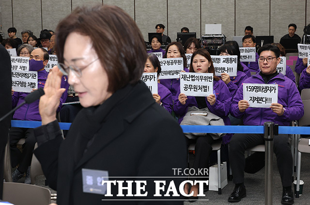 박희영 용산구청장이 13일 오전 서울 중구 은행회관에서 열린 10·29 이태원 참사 진상규명 청문회에 출석해 증인선서를 하는 가운데 유가족들이 책임자 처벌을 촉구하는 손팻말을 들고 있다. /송호영 기자