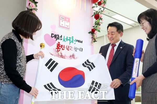 대전시 서구는 19일 혼인신고를 위해 구청을 방문한 국제결혼 부부에게 태극기를 증정했다. 서철모 서구청장이 구청 민원실을 방문한 국제결혼 부부에게 태극기를 전달하고 있다. /대전 서구