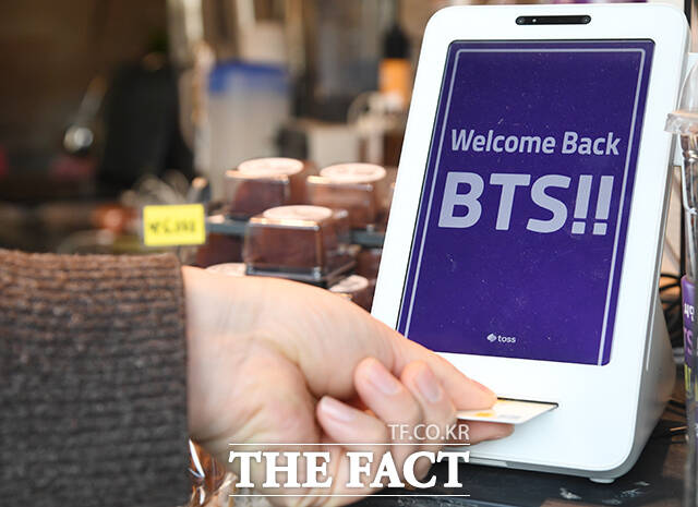 한 시민이 광화문광장 인근 카페에서 음료를 주문하는 가운데 키오스크 위로 BTS 컴백을 환영하는 문구가 보이고 있다.