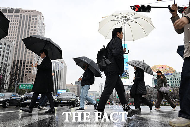 기후에너지환경부는 강우레이더와 인력을 기상청으로 이관해 24일부터 기상·강우레이더를 통합 운영한다. 사진은 지난 18일 오전 서울 종로구 광화문 네거리에서 우산을 쓴 시민들이 횡단보도를 건너고 있는 모습. /더팩트 DB
