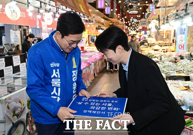 정원오 더불어민주당 서울시장 예비후보(왼쪽)가 6일 오후 서울 강북구 수유시장에서 김형남 전 서울시장 예비후보로부터 정책제안서를 받고 있다. /이새롬 기자