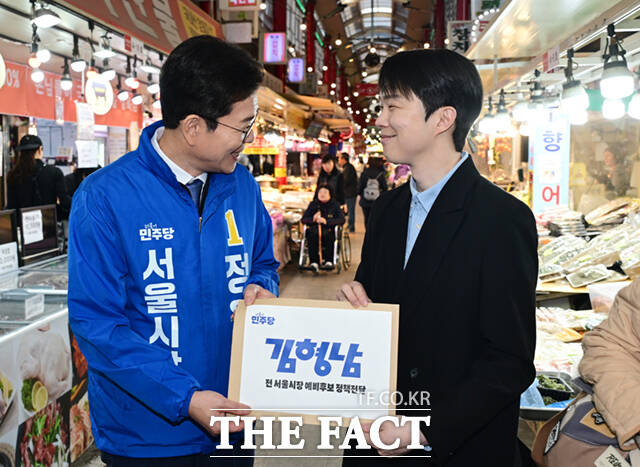 정원오 더불어민주당 서울시장 예비후보(왼쪽)가 6일 오후 서울 강북구 수유시장에서 김형남 전 서울시장 예비후보로부터 정책제안서를 받고 있다. /이새롬 기자