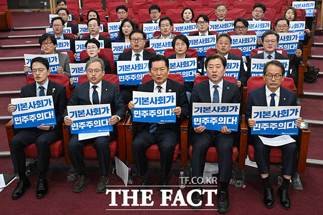 정청래 더불어민주당 대표(가운데)를 비롯한 참석자들이 7일 오전 서울 여의도 국회 의원회관에서 열린 민주당 기본사회위원회 3기 출범식에서 손피켓을 들고 구호를 외치고 있다. /국회=서예원 기자