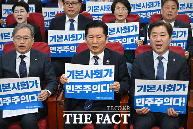 정청래 더불어민주당 대표(가운데)를 비롯한 참석자들이 7일 오전 서울 여의도 국회 의원회관에서 열린 민주당 기본사회위원회 3기 출범식에서 손피켓을 들고 구호를 외치고 있다. /국회=서예원 기자