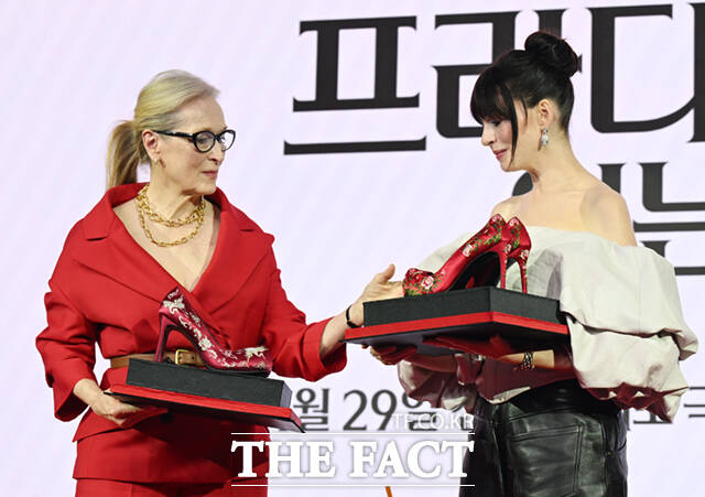 배우 메릴 스트립(왼쪽)과 앤 해서웨이가 8일 서울 광화문 포시즌스 호텔 서울에서 열린 영화 '악마는 프라다를 입는다2' 내한 기자간담회에서 제작진이 선물로 준비한 꽃신 하이힐을 받고 고개 숙여 인사하고 있다.