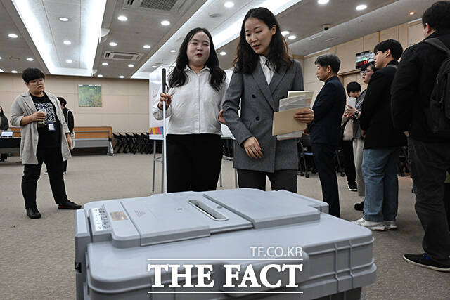 투표 보조인의 안내와 함께 투표함으로 이동하는 장애인 유권자.