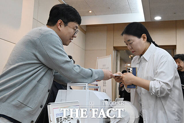 점자투표보조용구와 함께 투표용지를 수령받고 있는 유권자.