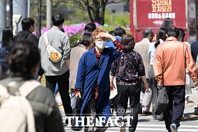 한 시민이 손으로 햇빛을 가린 채 발걸음을 옮기고 있다.