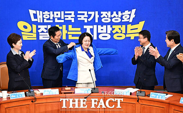 정청래 더불어민주당 대표(왼쪽 두번째)가 13일 오전 서울 여의도 국회에서 최고위원회의에 앞서 열린 추미애 경기도지사 후보자 환영식에 참석해 추 후보에게 파란색 점퍼를 입혀주고 있다.