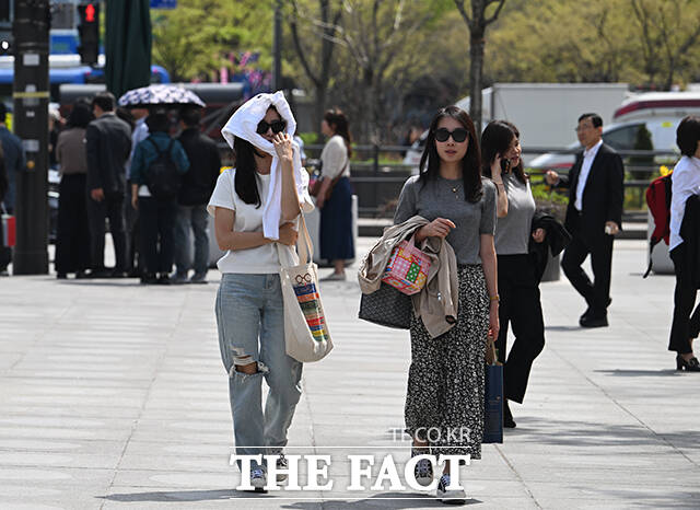 서울의 낮 최고기온이 27도까지 오르는 등 초여름 날씨를 보인 14일 오후 서울 종로구 광화문 광장을 찾은 시민들이 양산을 쓰고 걸음을 옮기고 있다. /박헌우 기자