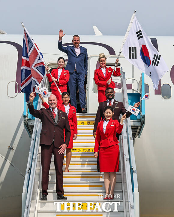 영국 버진애틀랜틱의 런던 히드로발 항공기에서 최고경영자 코닐 코스터(맨 위)와 승무원들이 취항을 기념하며 인사하고 있다. /공항사진기자단
