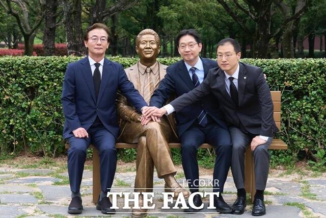 김경수 경남도지사 후보, 전재수 부산시장 후보, 김상욱 울산시장 후보가 노무현 전 대통령 동상 옆에 앉아 기념 촬영을 하고 있다. /김경수 선거 사무실