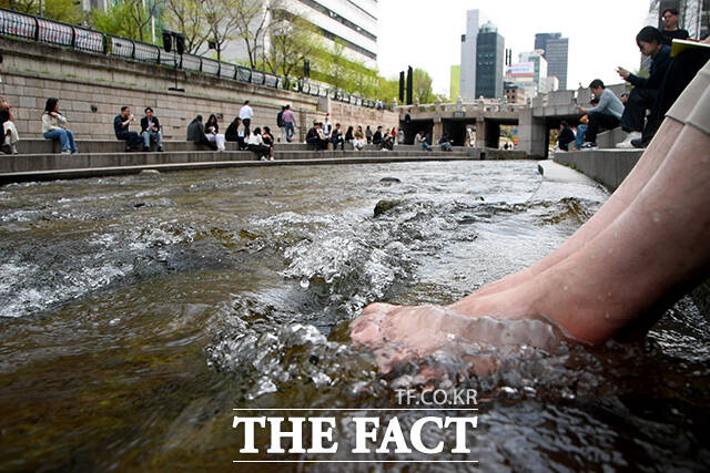서울 낮 최고 기온이 28도까지 오른 지난 14일 오후 서울 종로구 청계천에서 한 직장인이 청계천에 발을 담그고 있다. /박상민 기자