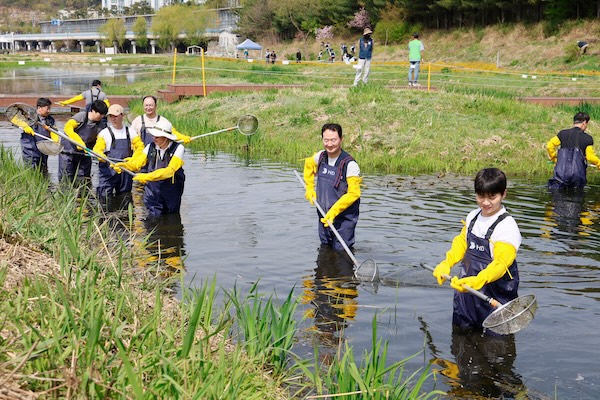 HD건설기계 임직원들이 성남 수내 습지에서 부유물을 제거하고 있다. /HD건설기계