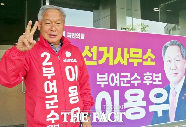 이용우 부여군수 후보가 선거사무소앞 현수막 앞에서 파이팅을 외치고 있다. /김형중 기자