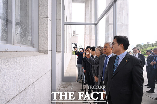 우원식 의장(왼쪽)에게 계엄군이 진입한 국회 의사당의 깨진 창문에 대한 설명 듣는 문 전 대통령.