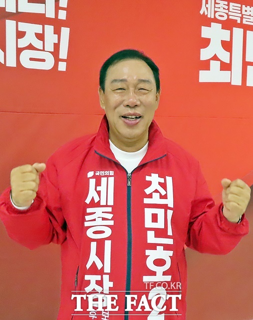 최민호 예비후보가 선거사무소 대형 현수막 앞에서 파이팅을 외치고 았다. /김형중 기자