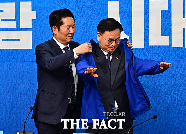 정청래 더불어민주당 대표(왼쪽)가 30일 오전 서울 여의도 국회에서 열린 3차 인재영입식에 참석해 6.3 재보궐선거 제주 서귀포시 후보로 영입한 김성범 전 해수부 차관에게 파란색 점퍼를 입혀주고 있다. /국회=배정한 기자