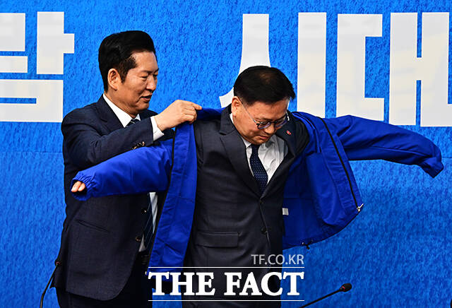 정청래 더불어민주당 대표(왼쪽)가 30일 오전 서울 여의도 국회에서 열린 3차 인재영입식에 참석해 6.3 재보궐선거 제주 서귀포시 후보로 영입한 김성범 전 해수부 차관에게 파란색 점퍼를 입혀주고 있다. /국회=배정한 기자