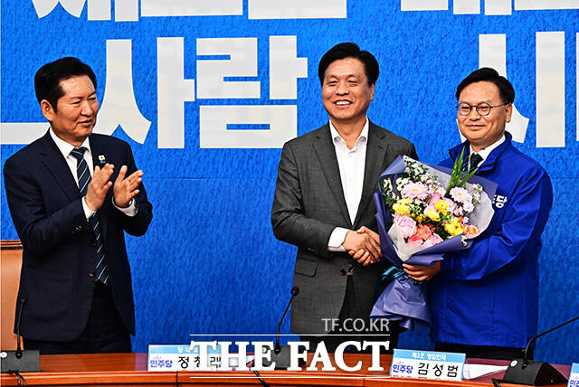 정청래 더불어민주당 대표(왼쪽)가 30일 오전 서울 여의도 국회에서 열린 3차 인재영입식에 참석해 6.3 재보궐선거 제주 서귀포시 후보로 영입한 김성범 전 해수부 차관에게 파란색 점퍼를 입혀주고 있다. /국회=배정한 기자