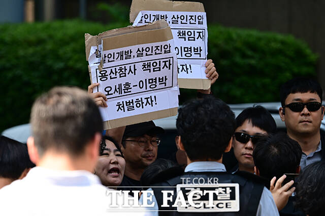 경호 인력에 제지 당한 시위자들이 '용산참사 책임자 오세훈 이명박'이라고 적힌 손팻말을 들고 있다.