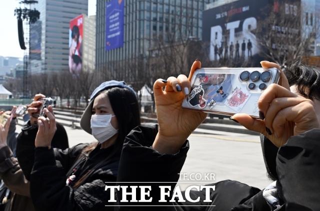 과거 K-POP은 음반과 공연 중심의 엔터테인먼트 산업으로 여겨졌지만 이제는 항공·숙박·패션·뷰티·외식·유통·관광·플랫폼 산업까지 연결되는 초대형 경제 생태계가 됐다. 사진은 지난 3월 서울 광화문광장 공연 하루 전 팬들이 BTS 광고 전광판을 촬영하고 있다. /이새롬 기자