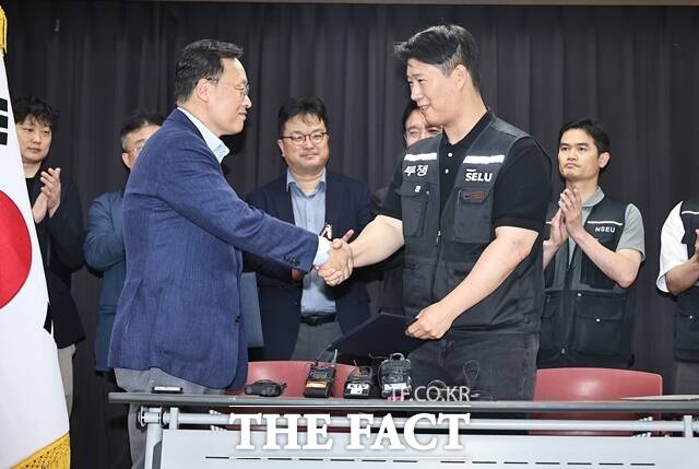 20일 경기도 수원시 장안구 경기고용노동청에서 열린 삼성전자 임금협상을 마친 후 여명구 삼성전자 DS부문 피플팀장(왼쪽)과 최승호 삼성그룹 초기업노동조합 삼성전자지부 위원장이 잠정 합의한에 서명한 후 손을 맞잡고 있다. /뉴시스