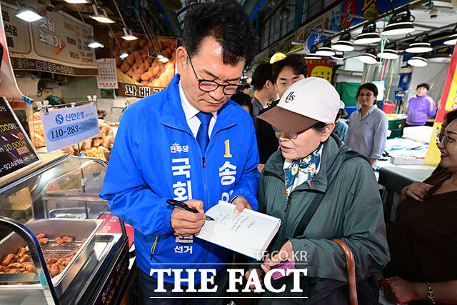송영길 더불어민주당 인천 연수갑 국회의원 보궐선거 후보가 20일 오후 인천 연수구 옥련시장에서 지지자가 건넨 자신의 서적에 인사말을 남기고 있다. /인천=남윤호 기자