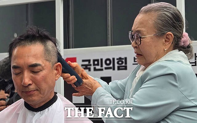 박민식 국민의힘 부산 북구갑 국회의원 후보의 어머니(오른쪽)가 21일 오후 부산 북구 구포시장 인근 쌈지공원에서 열린 출정식에서 박 후보의 머리를 삭발하고 있는 모습. /박민식 후보 캠프
