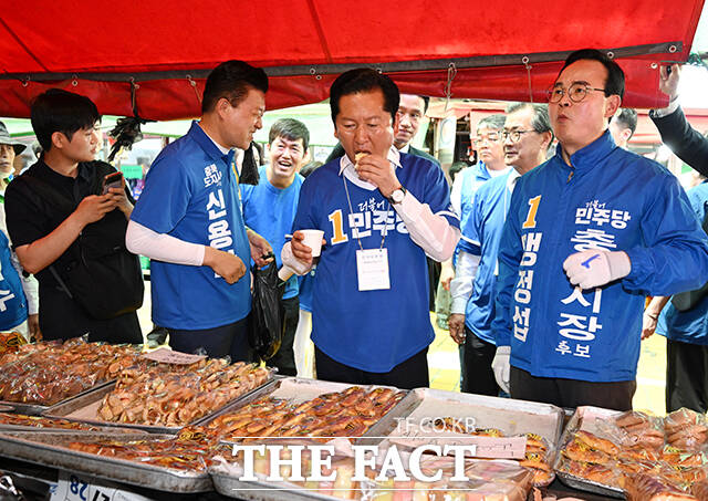 정청래 더불어민주당 총괄상임선대위원장(가운데)이 22일 오후 충북 충주시 충주공설시장을 찾아 구매한 빵을 시식하고 있다. /충주=박헌우 기자