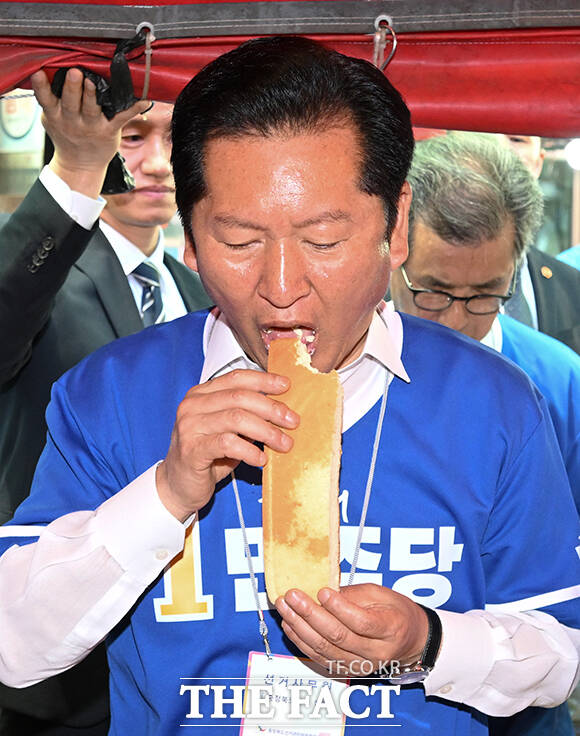 정청래 더불어민주당 총괄상임선대위원장(가운데)이 22일 오후 충북 충주시 충주공설시장을 찾아 구매한 빵을 시식하고 있다. /충주=박헌우 기자