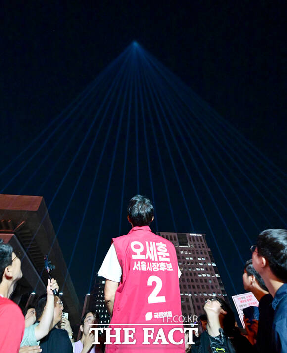오세훈 국민의힘 서울시장 후보가 제9회 전국동시지방선거 본투표를 하루 앞둔 2일 서울 광화문광장 감사의정원을 찾아 상공 한 군데로 모여지는 빛줄기를 바라보고 있다.
