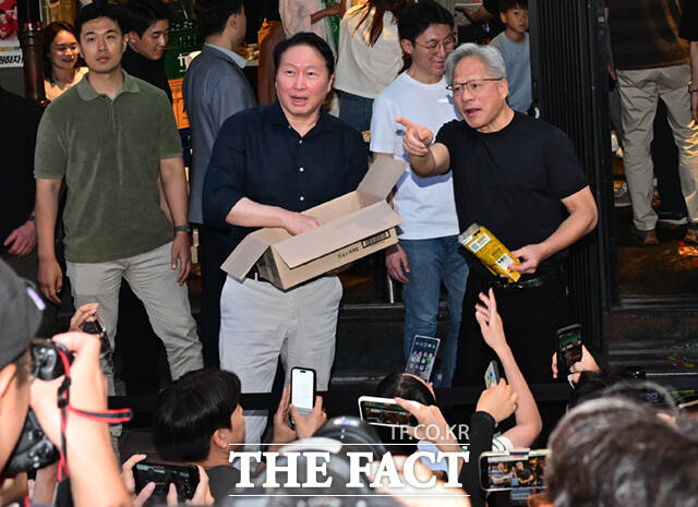 젠슨 황 엔비디아 최고경영자가 5일 오후 서울 마포구 서교동의 한 고깃집 앞에서 최태원 SK회장과 함께 'HBM칩스'를 시민들에게 나눠주고 있다. /이새롬 기자