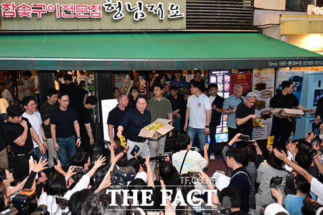 젠슨 황 엔비디아 최고경영자(CEO)가 5일 서울 마포구 서교동의 한 고깃집에서 최태원 SK회장, 구광모 LG회장, 이해진 네이버 의장과 삼겹살 회동을 하는 도중 시민들에게 SK에서 만든 ‘HBM’칩스를 전달하고 있다. /이새롬 기자
