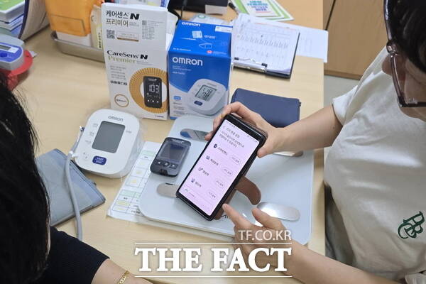 계룡시보건소 관계자가 'AI·IoT 기반 어르신 건강관리 사업' 참여자를 대상으로 스마트폰 앱과 건강측정기기 사용 방법을 안내하고 있다. /계룡시