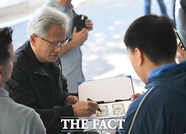 젠슨 황 엔비디아 최고경영자(CEO)가 9일 서울 강서구 서울김포비즈니스항공센터에서 출국하며 팬들이 준비한 지폐에 사인하고 있다.