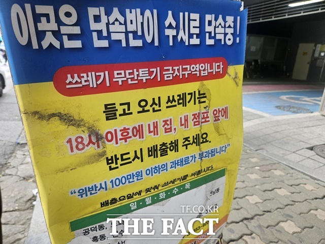 '이곳은 단속반이 수시로 단속 중. 쓰레기 무단투기 금지구역', '들고 온 쓰레기는 오후 6시 이후 내 집, 내 점포 앞에 배출. 위반 시 100만원 이하의 과태료 부과' 등 경고 문구가 적힌 노란 안내판도 설치돼 있었다. 하지만 정작 안내판 일부가 찢어진 탓에 문구가 가려져 제대로 보이지 않았다. /이다빈 기자