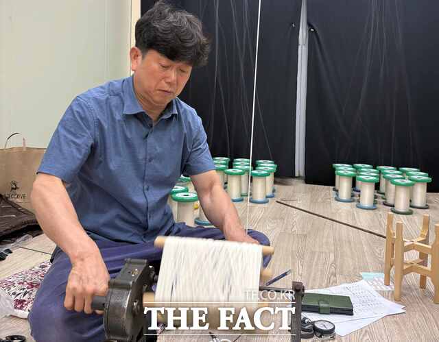 김동환 가야금 명장이 우륵박물관 가야금줄 제작 체험장에서 전통 방식으로 가야금줄을 꼬는 시연을 하고 있다. 누에고치에서 얻은 생사가 장인의 손길을 거쳐 가야금의 맑은 선율을 만들어내는 줄로 완성된다. /고령군