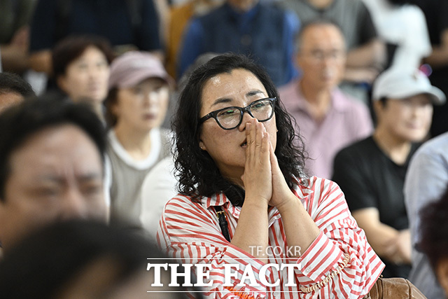 한 시민이 두 손을 모은 채 경기를 보고 있다.