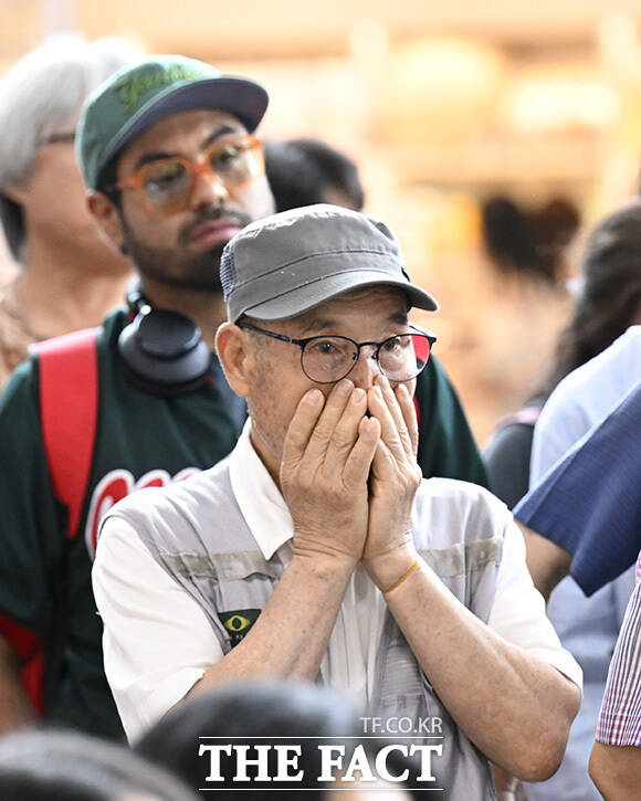 한 시민이 두 손을 모은 채 경기를 보고 있다.