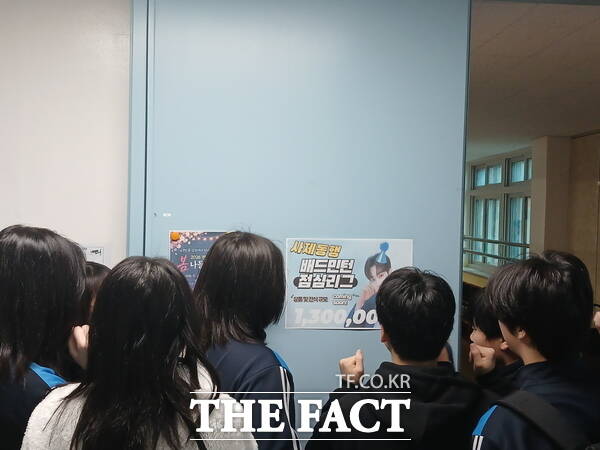 대전문지중학교 학생들이 학교 한편에 게시된 사제동행 배드민턴 리그전 홍보 포스터를 살펴보고 있는 모습. /대전시교육청
