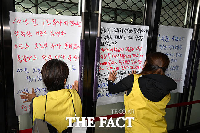 노조원들이 기자회견을 마친 후 면담 연기 규탄 대자보를 붙이고 있다.