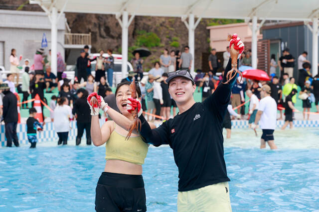 18일 천부 해수풀장에서 맨손으로 오징어를 잡은 관광객 부부가 포즈를 취하고 있다. /울릉군