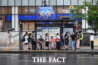 버스 정류장에서 비 피하는 시민들 [포토]