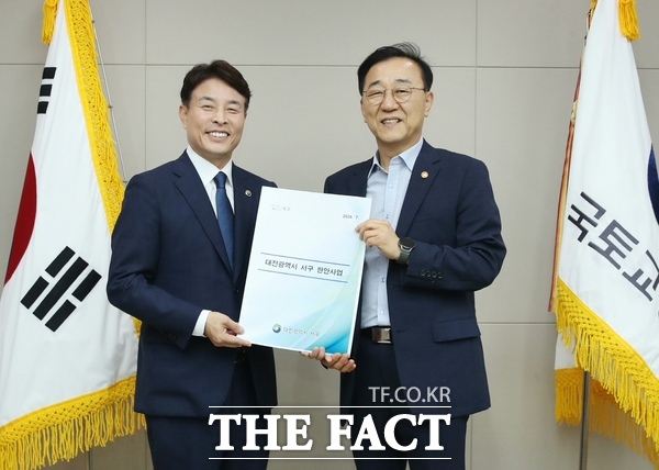 전문학 대전시 서구청장(왼쪽)이 김윤덕 국토교통부 장관에게 현안 사업 계획안을 전달하고 있다. /대전시 서구