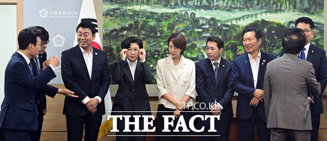 기념촬영을 위해 참석자들이 나란히 선 가운데, 아직 자리를 잡지 않은 김민석 예비후보(왼쪽)를 바라보는 후보들.