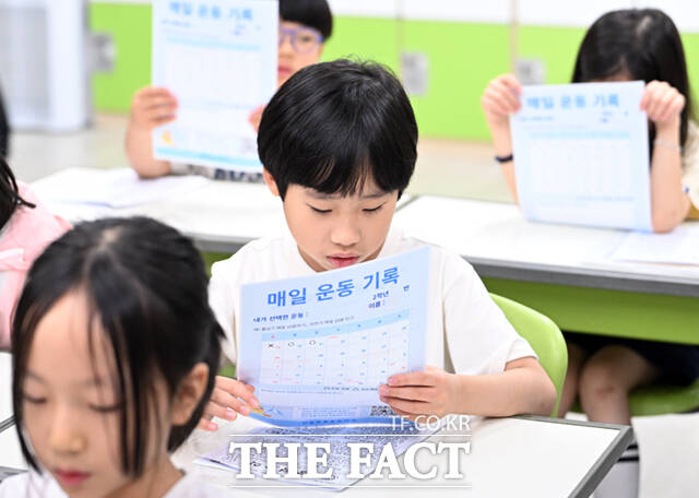 22일 오후 서울 노원구 중평초등학교 2학년 2반 어린이들이 여름방학식에서 생활계획표가 담긴 부채를 들어보이고 있다.