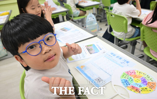 22일 오후 서울 노원구 중평초등학교 2학년 2반 어린이들이 여름방학식에서 생활계획표가 담긴 부채를 들어보이고 있다.