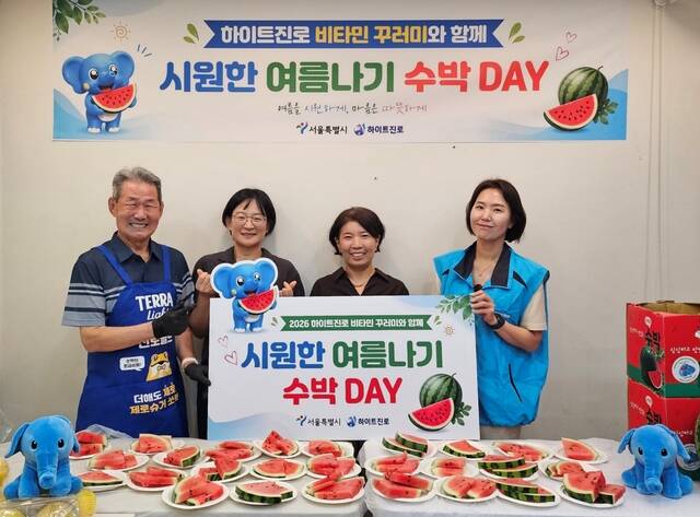 지난 22일 서울역 쪽방촌에서 2026 하이트진로 비타민 꾸러미와 함께 시원한 여름나기 ‘수박 DAY' 행사가 열렸다. (왼쪽부터) 쪽방촌 주민, 서울시 이신옥 팀장, 서울역 쪽방상담소 유호연 소장, 하이트진로 관계자가 기념 촬영을 하고 있다. /하이트진로
