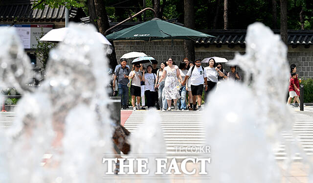 서울광장 분수대가 동작하는 가운데 시민들이 길을 건너고 있다.